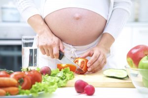 Pregnant woman in kitchen making salad