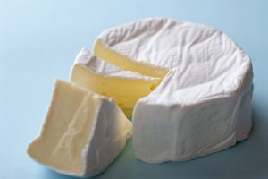 Round soft brie cheese with a wedge removed, closeup high angle view